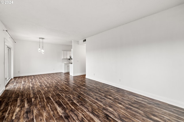 unfurnished living room featuring dark hardwood / wood-style flooring and a chandelier