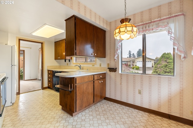 kitchen with stainless steel range oven, sink, white fridge, and decorative light fixtures