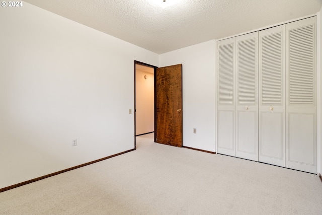 unfurnished bedroom with light colored carpet, a textured ceiling, and a closet