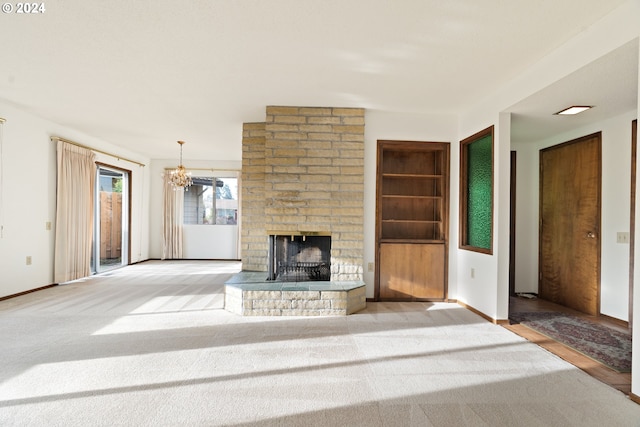 unfurnished living room with light colored carpet, a brick fireplace, and a notable chandelier