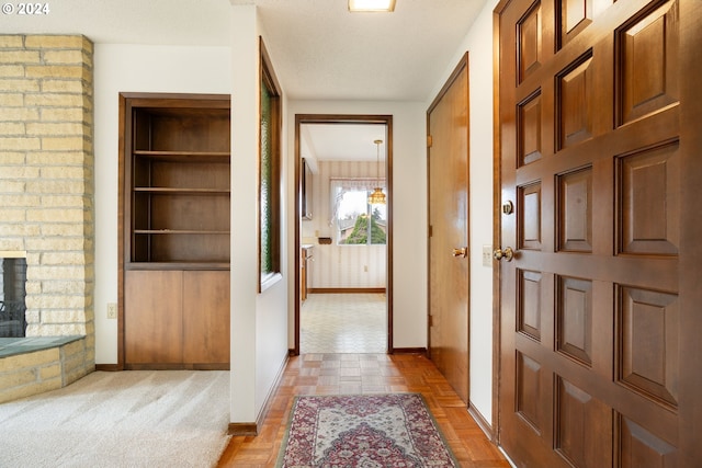 hallway featuring a textured ceiling and light colored carpet