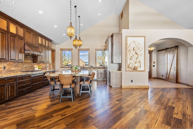 dining room featuring a barn door, dark hardwood / wood-style floors, high vaulted ceiling, and sink