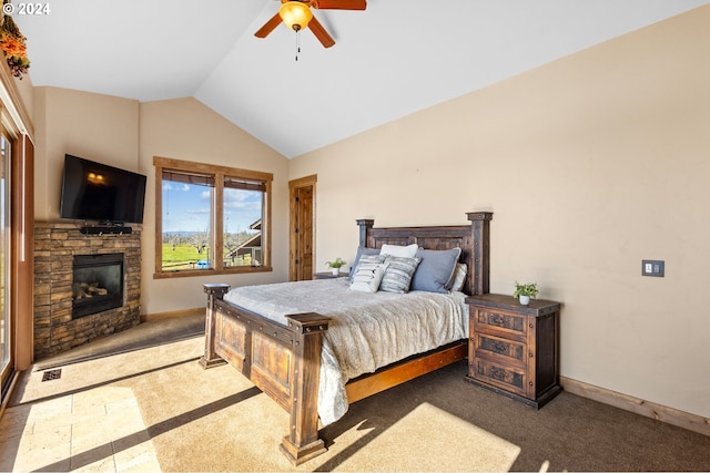 bedroom with dark carpet, ceiling fan, lofted ceiling, and a stone fireplace