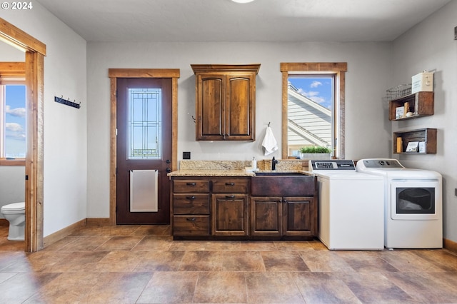 washroom with washing machine and clothes dryer, sink, and cabinets