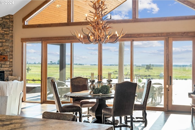 dining space with a water view, vaulted ceiling, light hardwood / wood-style floors, a rural view, and a chandelier