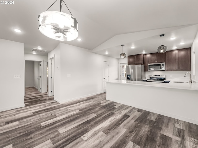 kitchen with dark brown cabinetry, stainless steel appliances, decorative light fixtures, and hardwood / wood-style flooring