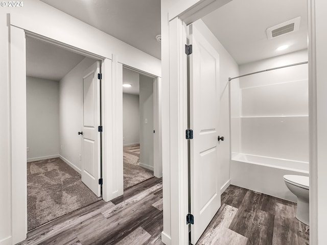 bathroom featuring toilet, tub / shower combination, and hardwood / wood-style flooring