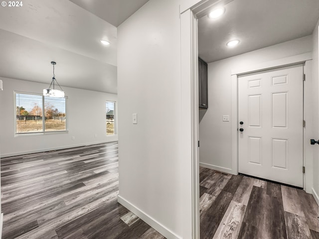 entryway featuring dark wood-type flooring and an inviting chandelier