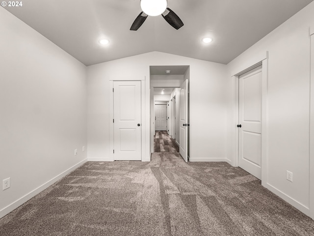 unfurnished bedroom featuring dark carpet, vaulted ceiling, and ceiling fan