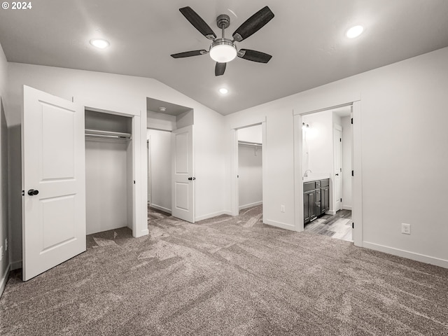 unfurnished bedroom featuring carpet flooring, ensuite bath, ceiling fan, and lofted ceiling