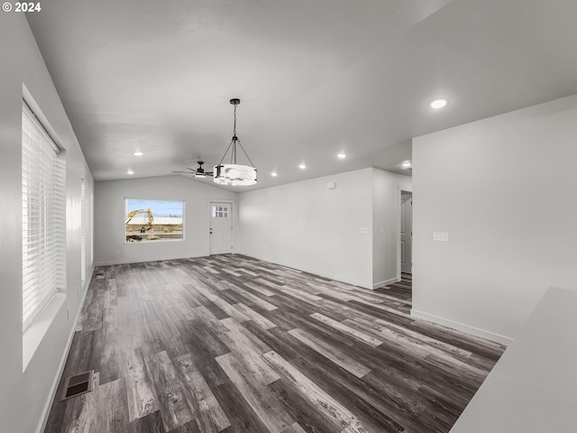 unfurnished living room with dark hardwood / wood-style flooring, ceiling fan with notable chandelier, and vaulted ceiling