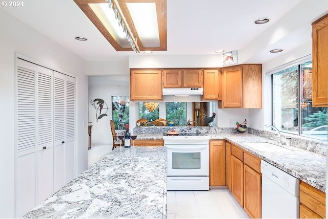 kitchen with sink, white appliances, light stone countertops, and plenty of natural light