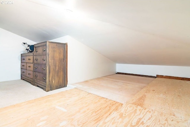 additional living space featuring light colored carpet and vaulted ceiling