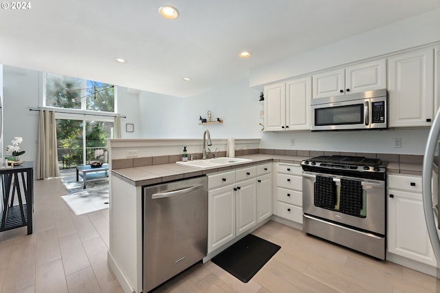 kitchen with kitchen peninsula, white cabinetry, sink, and stainless steel appliances