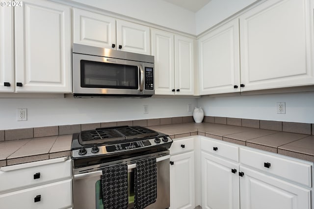 kitchen with white cabinets, stainless steel appliances, and tile countertops