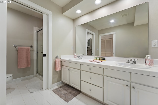 bathroom with tile patterned flooring, vanity, toilet, and a shower with shower door