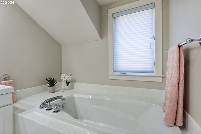 bathroom featuring tiled tub and vanity