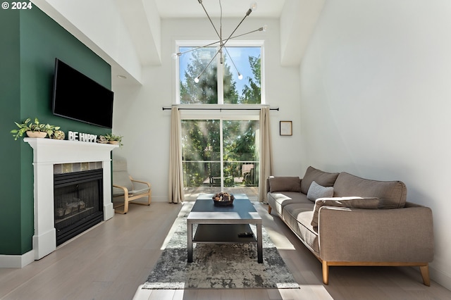 living room with a towering ceiling, a tiled fireplace, hardwood / wood-style flooring, and a healthy amount of sunlight