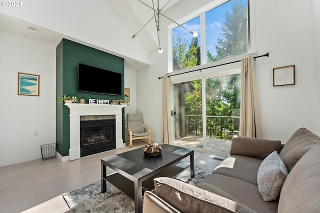 living room with high vaulted ceiling, light wood-type flooring, and a fireplace