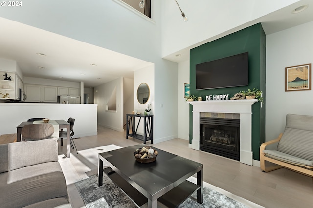 living room featuring a high ceiling, a fireplace, and light hardwood / wood-style floors