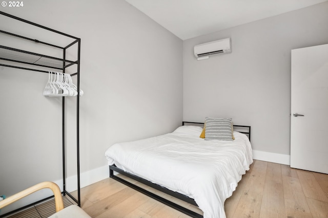 bedroom with hardwood / wood-style flooring and a wall unit AC