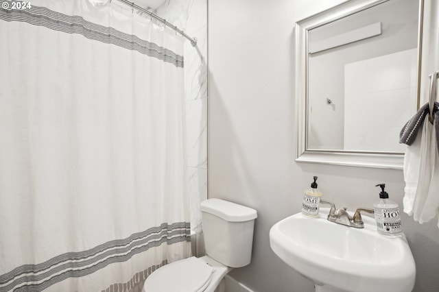 bathroom featuring a shower with shower curtain, toilet, and sink