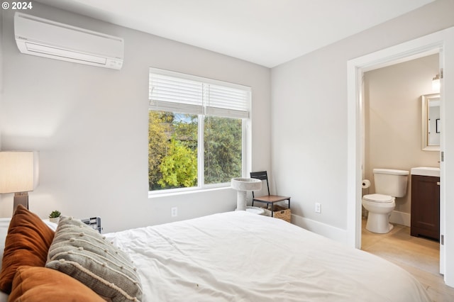 bedroom featuring connected bathroom and a wall mounted air conditioner