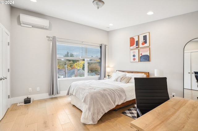 bedroom with a wall mounted air conditioner and light hardwood / wood-style floors