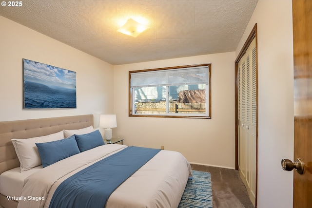 bedroom with a textured ceiling, dark carpet, and a closet