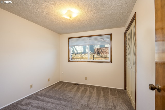 unfurnished bedroom with dark carpet, a closet, and a textured ceiling