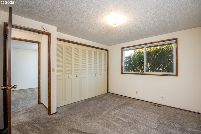 unfurnished bedroom with carpet floors, a textured ceiling, and a closet