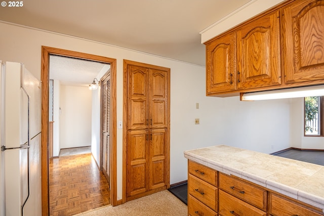 kitchen with tile counters, light parquet flooring, and white fridge