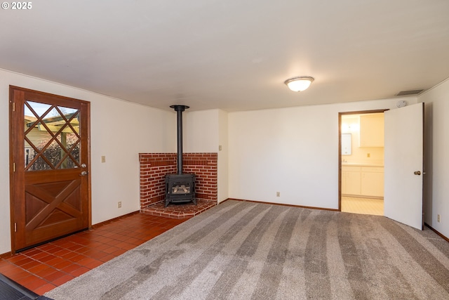 unfurnished living room featuring carpet floors and a wood stove