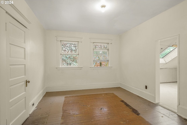 spare room featuring wood-type flooring and a skylight