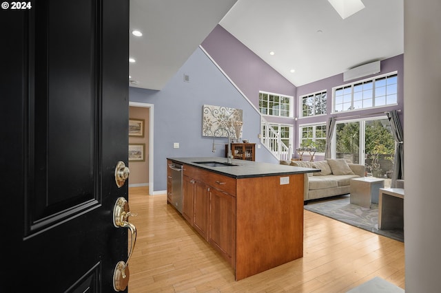 kitchen featuring a wall unit AC, light wood-type flooring, a sink, dishwasher, and open floor plan