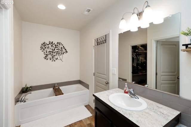 27309 8th St, Junction City, OR 97448 - bathroom with vanity, a spacious closet, visible vents, a garden tub, and wood finished floors