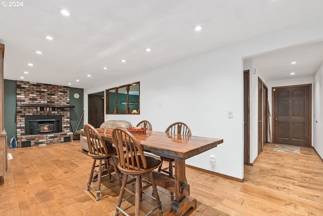 dining room featuring light wood-type flooring and a brick fireplace