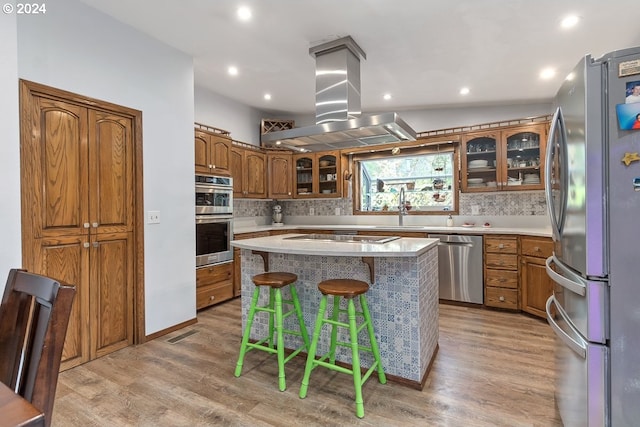 kitchen with a center island, island range hood, stainless steel appliances, and light hardwood / wood-style flooring