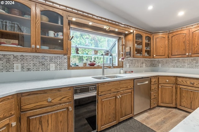 kitchen featuring dishwasher, backsplash, vaulted ceiling, and sink