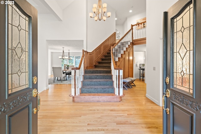 foyer with a high ceiling, light hardwood / wood-style flooring, and a notable chandelier