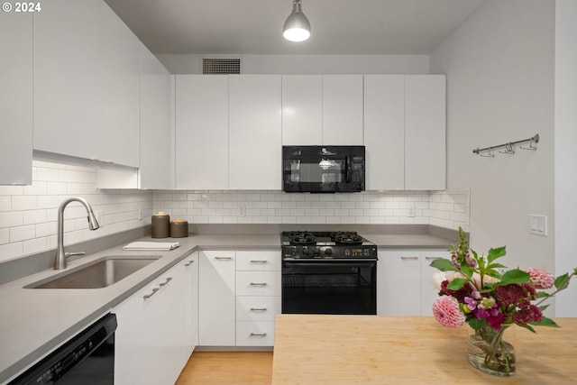 kitchen featuring sink, white cabinetry, decorative backsplash, and black appliances