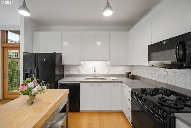 kitchen with pendant lighting, sink, white cabinets, and black appliances