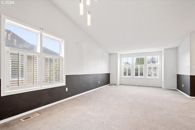 empty room featuring plenty of natural light, light colored carpet, and lofted ceiling