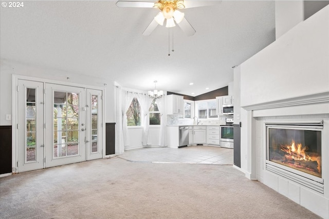 unfurnished living room with lofted ceiling, light carpet, a tile fireplace, sink, and a textured ceiling