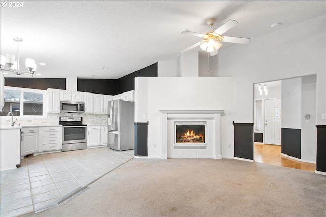 interior space with light carpet, appliances with stainless steel finishes, white cabinets, and hanging light fixtures