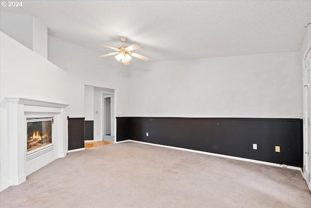 unfurnished living room with a textured ceiling, light colored carpet, and ceiling fan