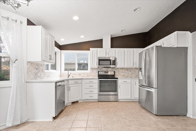 kitchen featuring sink, white cabinets, stainless steel appliances, and lofted ceiling