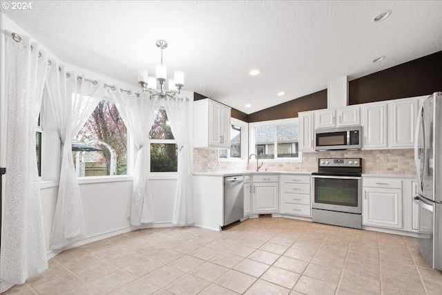 kitchen featuring pendant lighting, stainless steel appliances, a wealth of natural light, and lofted ceiling