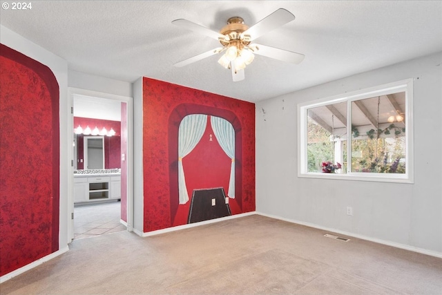 carpeted spare room featuring a textured ceiling and ceiling fan