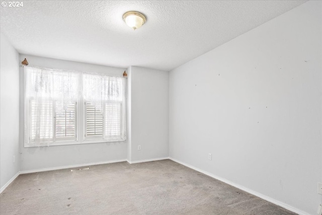 unfurnished room with a textured ceiling and light colored carpet